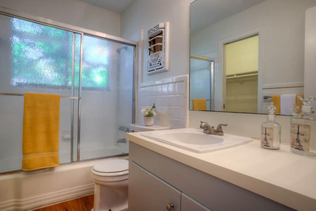302 East 34th Street, Unit 201 Austin, TX 78705 - Photo 4 of 6 Full bath with vanity, a walk in closet, shower / bath combination with glass door, and dark wood-style floors