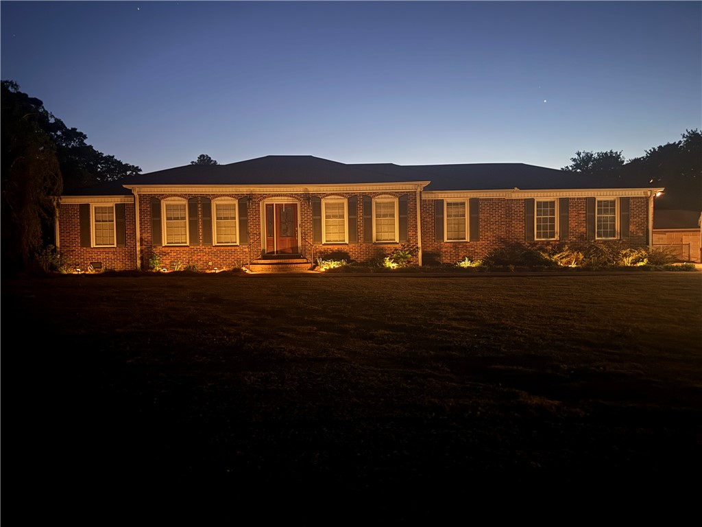 Illuminated brick facade with architectural windows creates a captivating evening presence.