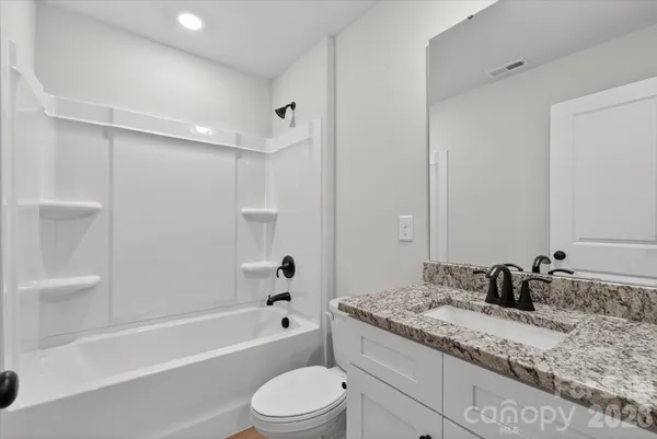a bathroom with a granite countertop sink a toilet and bathtub