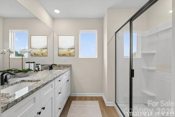 a bathroom with a granite countertop sink a mirror and a shower