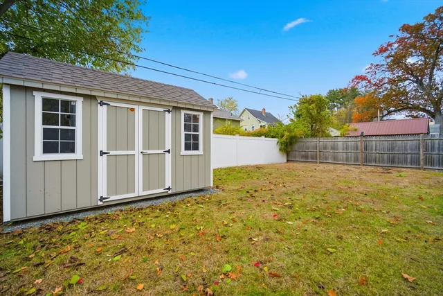 a view of backyard with large trees and wooden fence