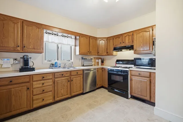 a kitchen with granite countertop white cabinets sink and stainless steel appliances