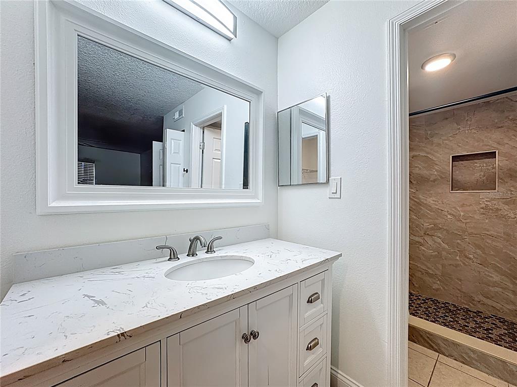 185 Waterfall Way, Unit 102 Altamonte Springs, FL 32714 - Photo 40 of 59 a bathroom with a granite countertop sink a mirror and a shower
