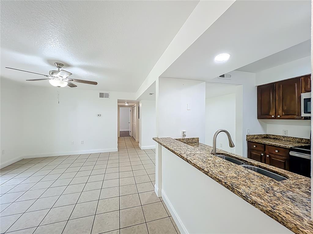 185 Waterfall Way, Unit 102 Altamonte Springs, FL 32714 - Photo 7 of 59 a kitchen with granite countertop a sink a stove cabinets and a counter top space