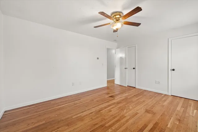 an empty room with wooden floor and ceiling fan