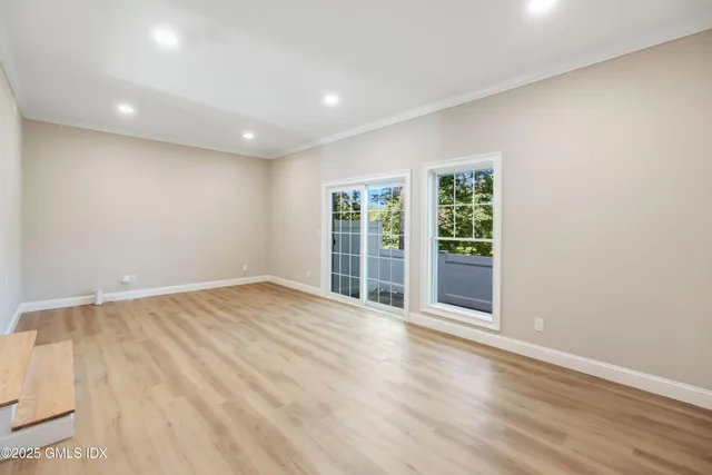 a view of an empty room with wooden floor and a window