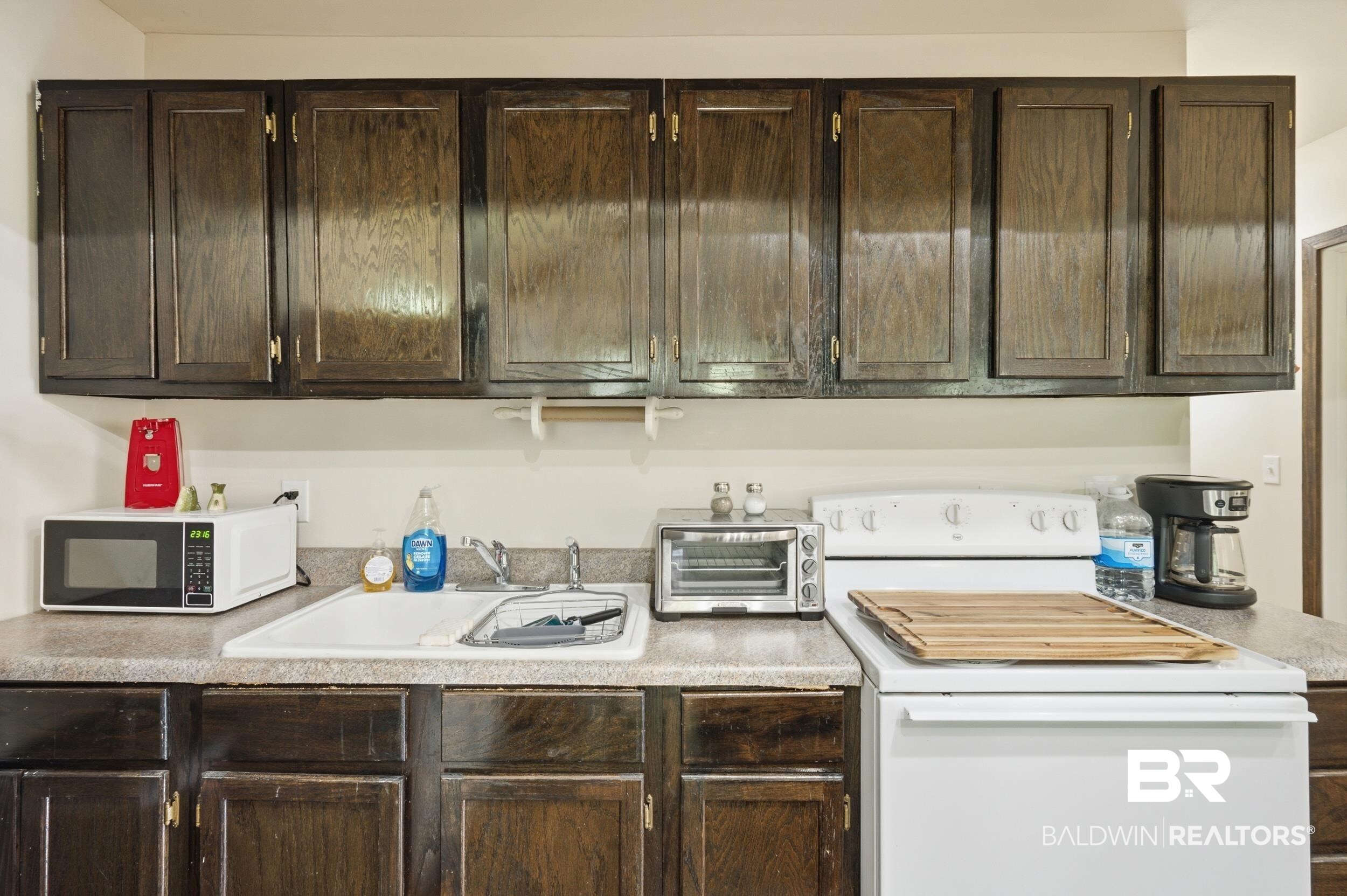 42080 Bayou Road Bay Minette, AL 36507 - Photo 14 of 43 Kitchen featuring dark wood-finish cabinetry, a white drop-in sink, and a light-toned countertop