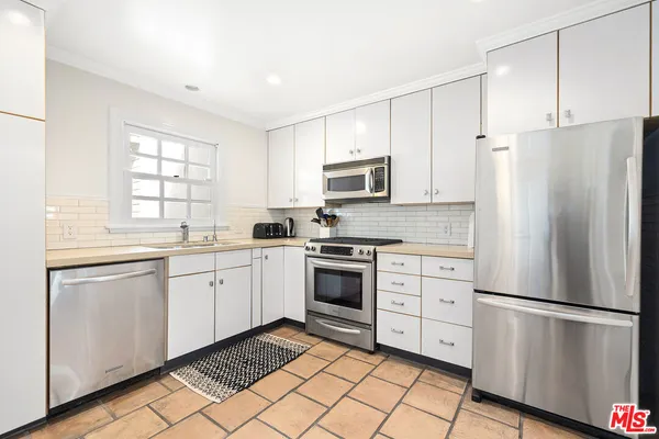 a kitchen with white cabinets stainless steel appliances and a window