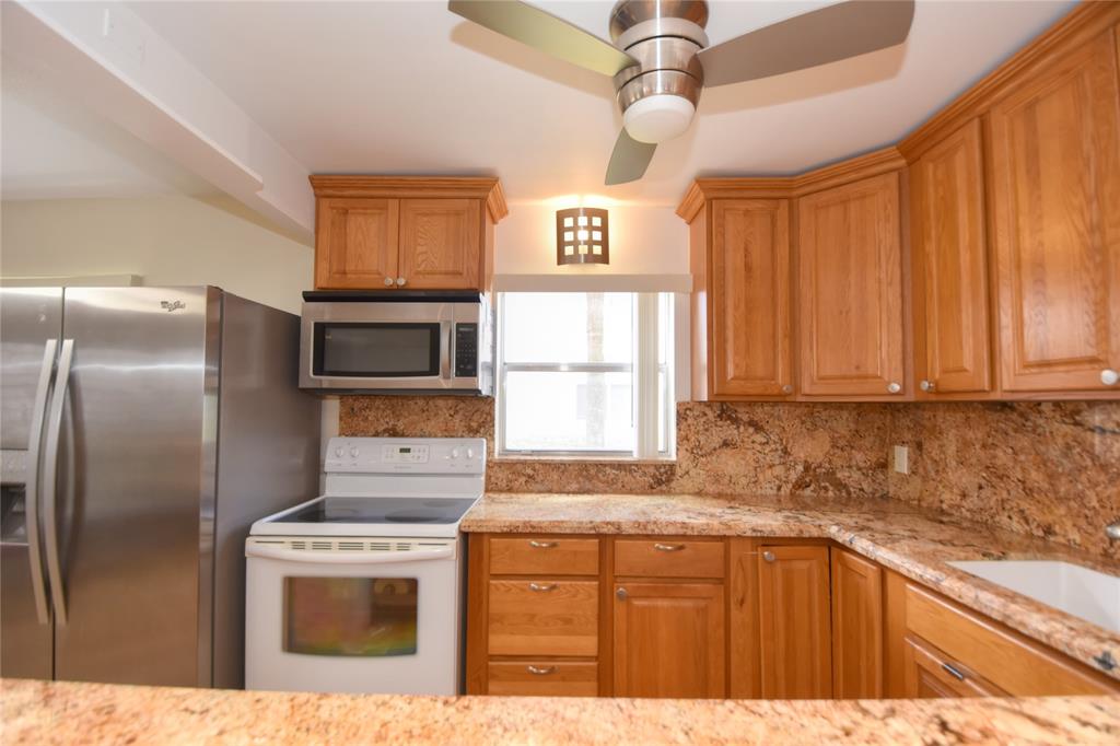 357 Saxony Lane, Unit 357 Delray Beach, FL 33446 - Photo 12 of 35 a kitchen with stainless steel appliances granite countertop a refrigerator a sink dishwasher a stove and white countertops with cabinets
