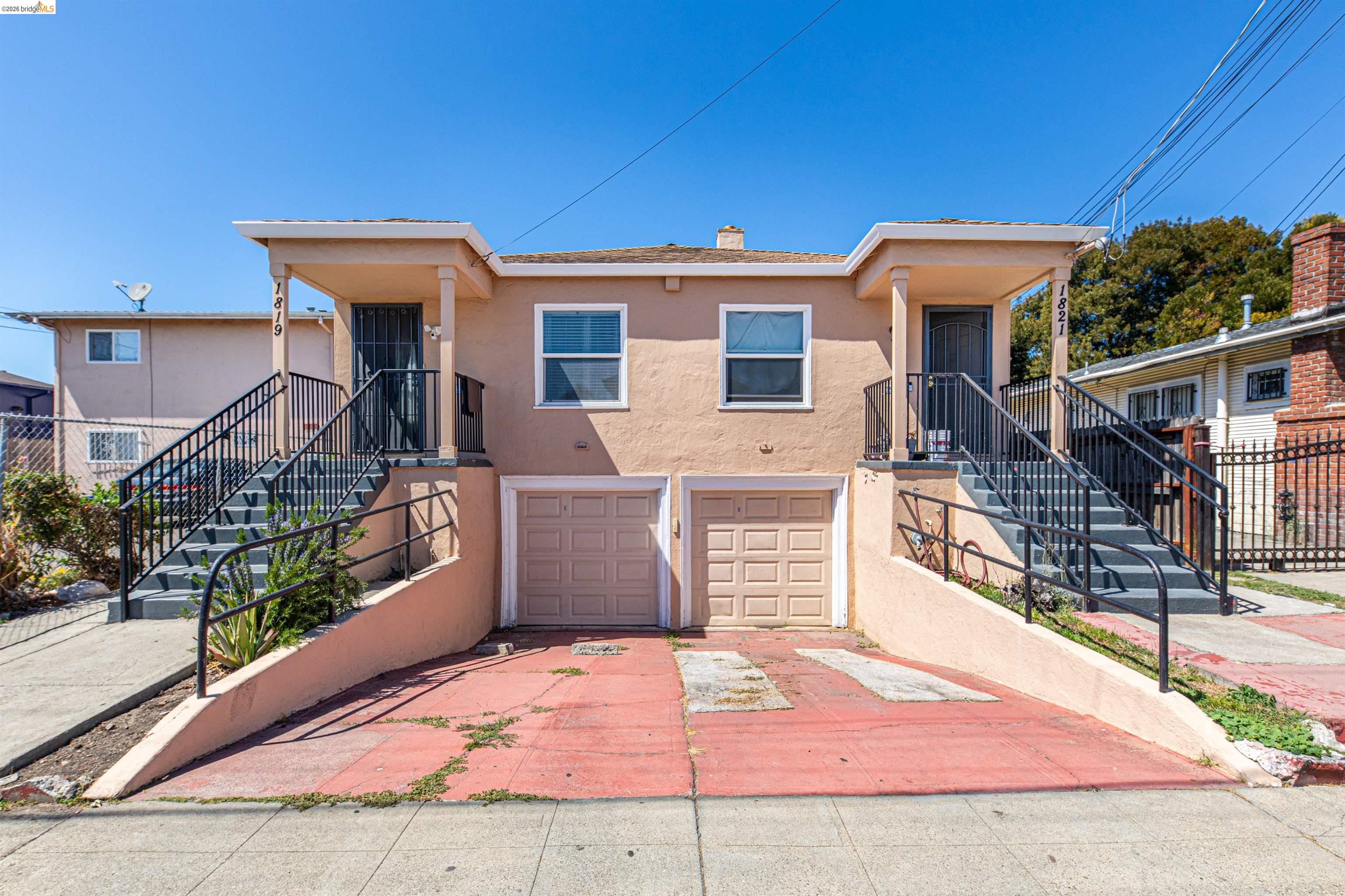 1821 74th Avenue Oakland, CA 94621 - Photo 1 of 27 View of front of property with stairs, stucco siding, a chimney, and concrete driveway
