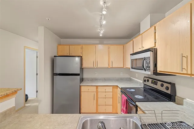 a kitchen with stainless steel appliances granite countertop a refrigerator a stove top oven a sink and dishwasher