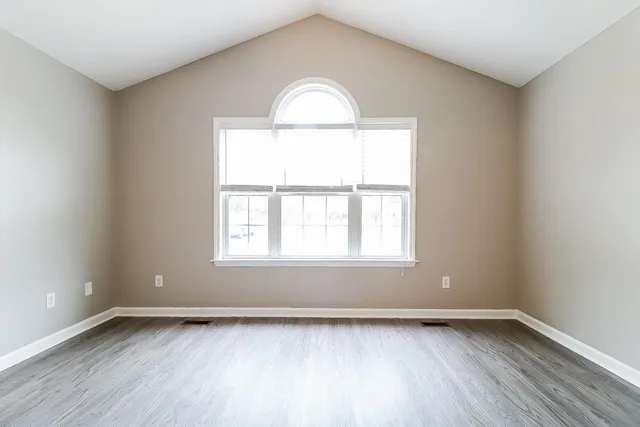 an empty room with wooden floor and a window