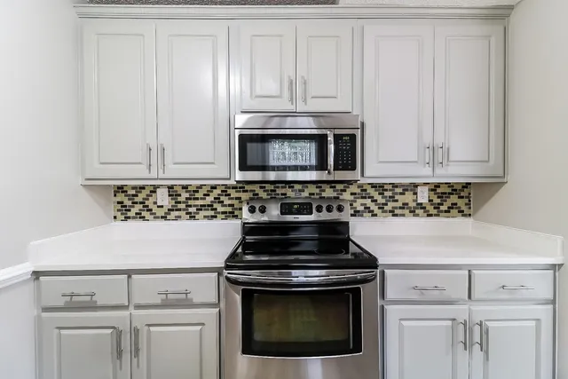 a kitchen with granite countertop white cabinets and stainless steel appliances