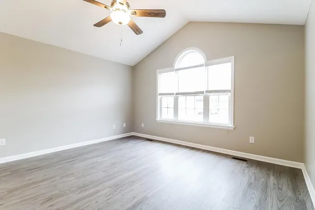 an empty room with wooden floor chandelier and windows