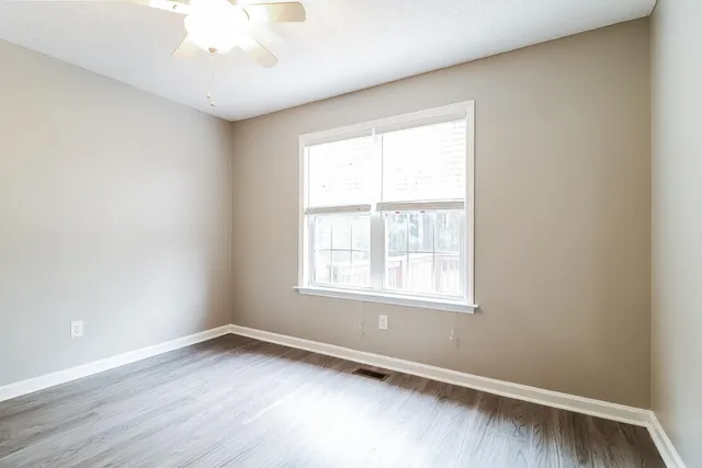 an empty room with wooden floor and windows