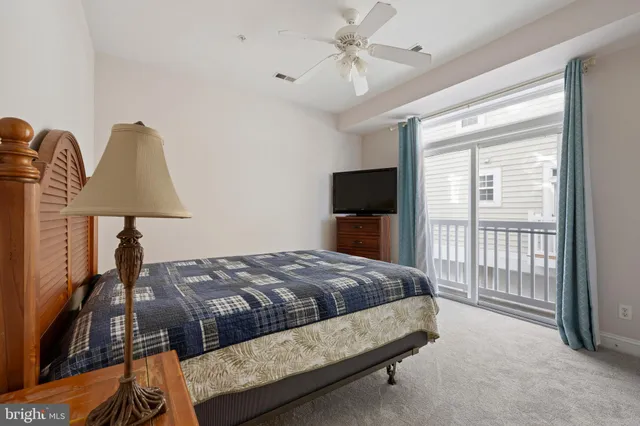 a bedroom with a bed lamp on desk and a window