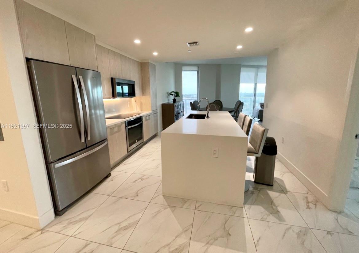 2000 Metropica Way, Unit 1009 Sunrise, FL 33323 - Photo 11 of 40 a kitchen with stainless steel appliances a refrigerator sink and microwave