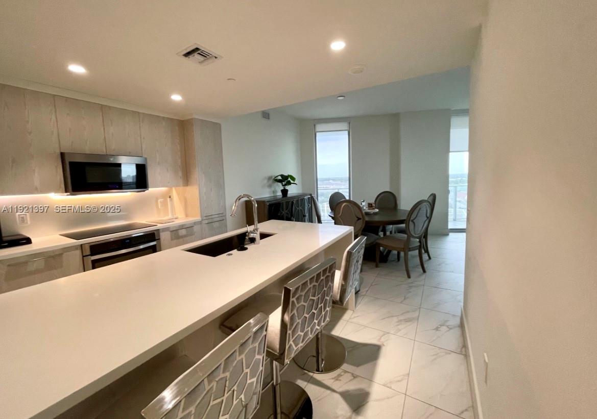 2000 Metropica Way, Unit 1009 Sunrise, FL 33323 - Photo 14 of 40 a kitchen with stainless steel appliances a sink a stove a table and chairs