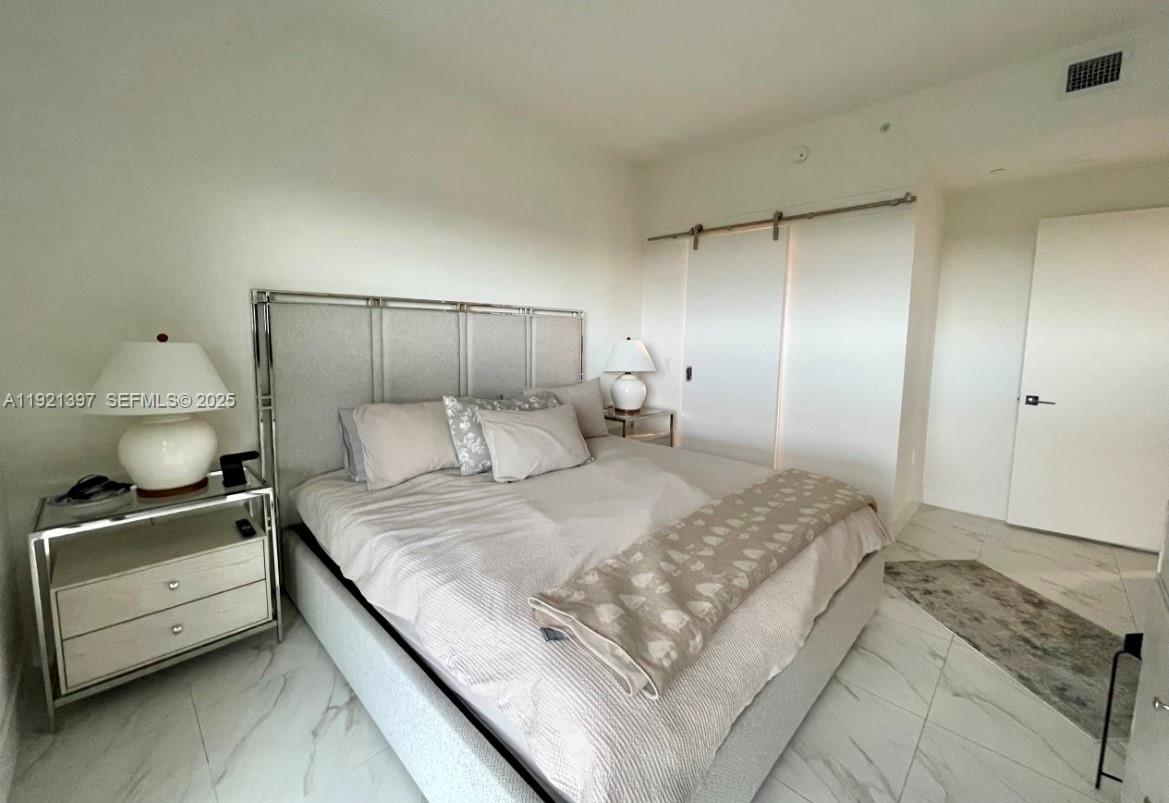 2000 Metropica Way, Unit 1009 Sunrise, FL 33323 - Photo 19 of 40 a bedroom with a bed and a tv on the dresser