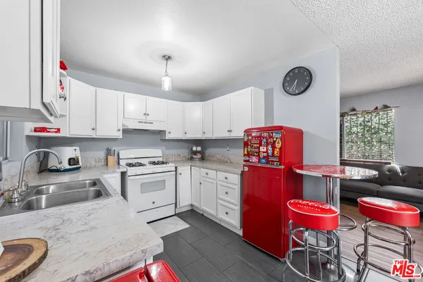 a kitchen with granite countertop a sink a stove and wooden floors