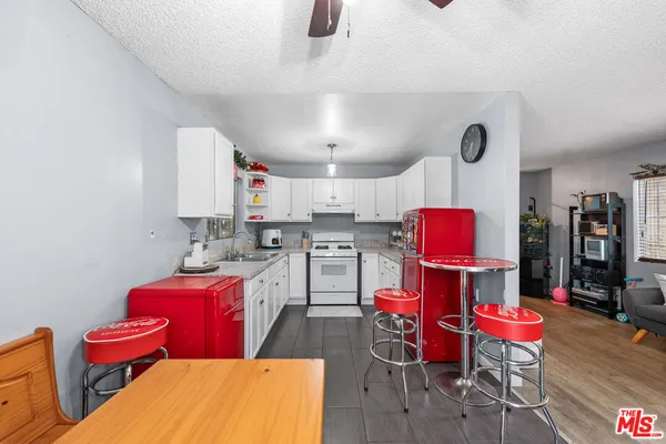 a kitchen with stainless steel appliances kitchen island granite countertop a dining table chairs sink and cabinets
