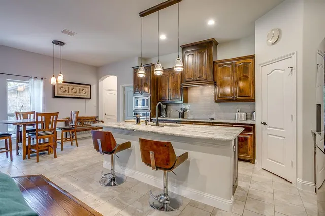 a kitchen with stainless steel appliances granite countertop a sink a stove and a wooden floors