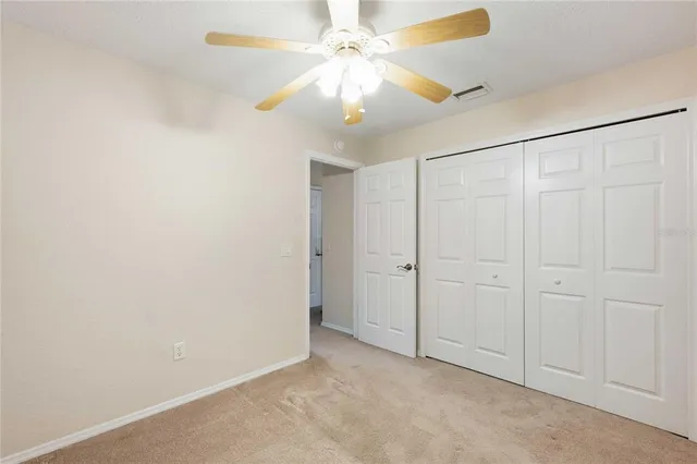 an empty room with a chandelier fan and closet