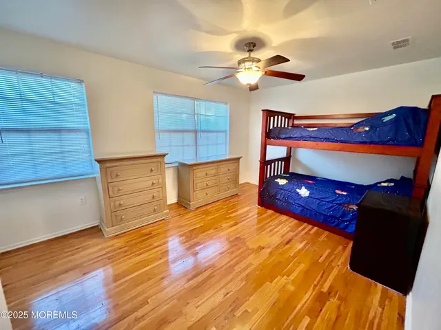 a bedroom with wooden floor and ceiling fan