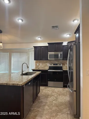 a kitchen with stainless steel appliances granite countertop a sink stove and refrigerator