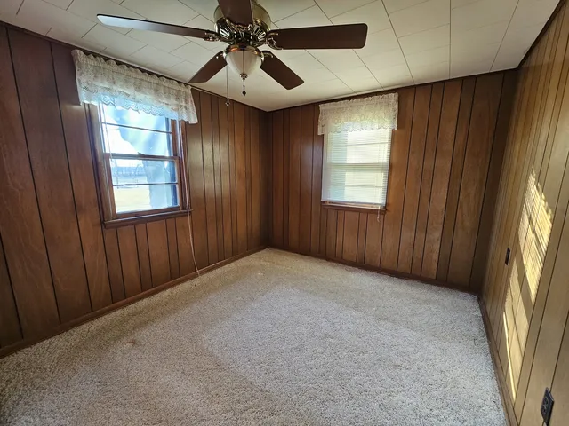 an empty room with windows and fan