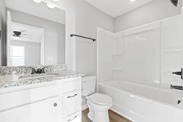a bathroom with a granite countertop sink toilet mirror and bathtub