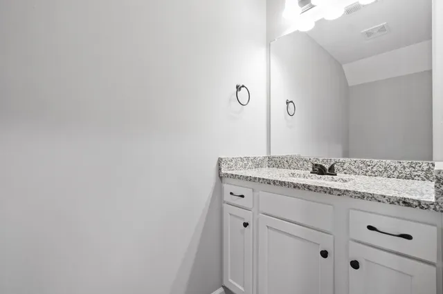 a bathroom with a granite countertop sink and mirror