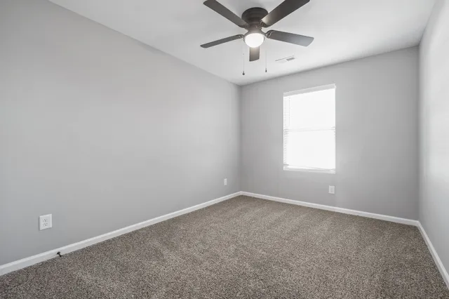 an empty room with a window and a fan