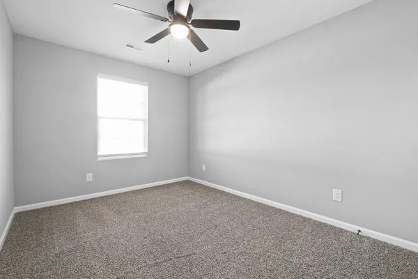 an empty room with a window and a fan