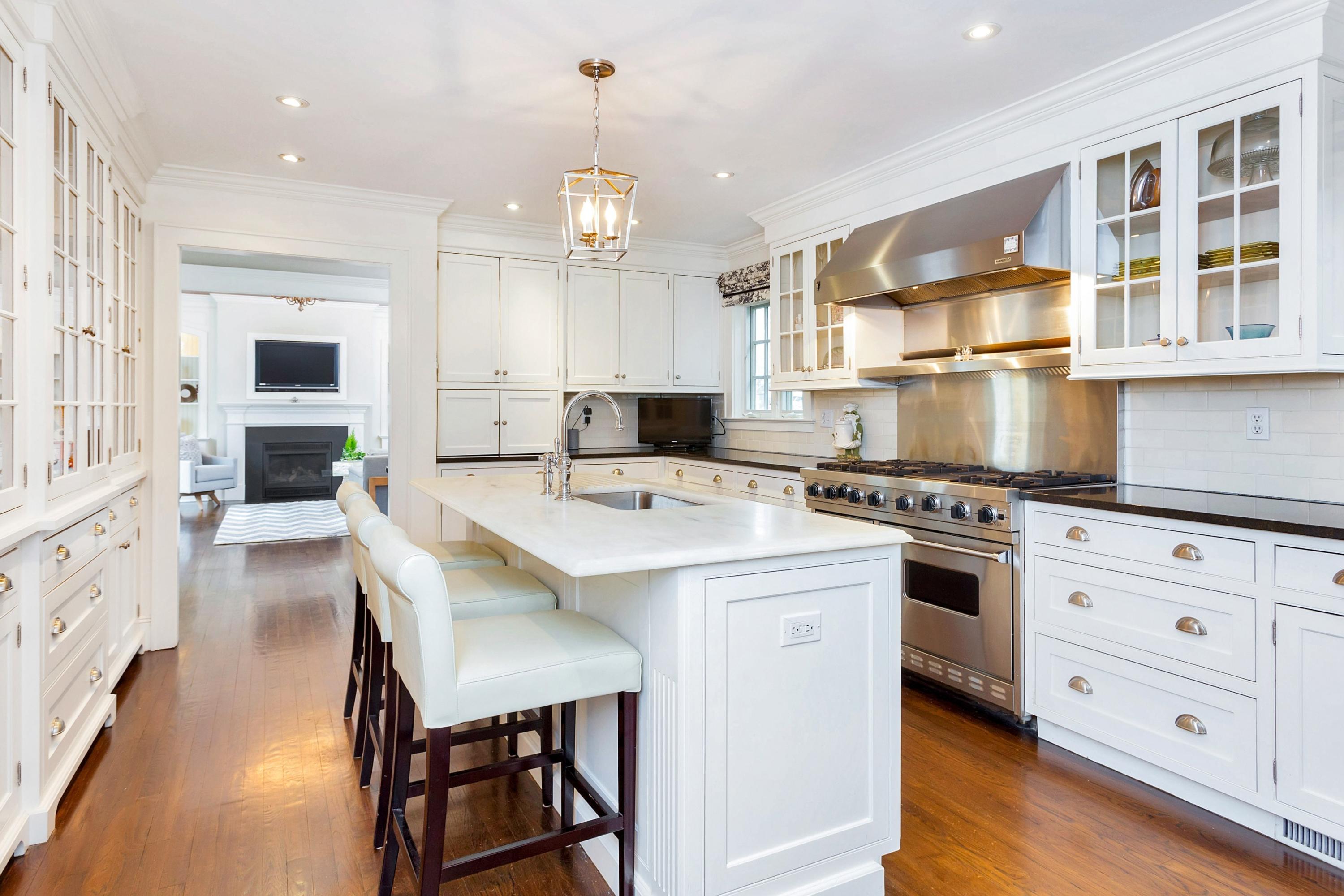 12 Dorchester Lane Riverside, CT 06878 - Photo 11 of 35 a kitchen with stainless steel appliances kitchen island granite countertop a stove a sink a dining table and chairs with white cabinets