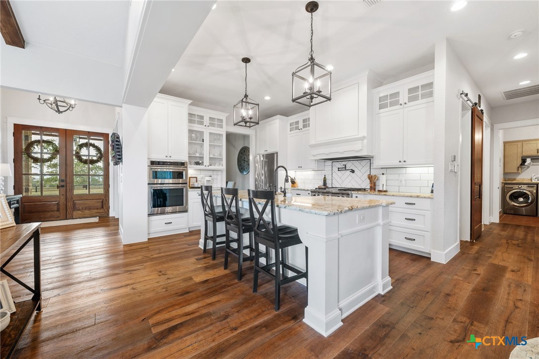 1665 Sunflower Trail Luling, TX 78648 - Photo 13 of 46 a large kitchen with cabinets chairs and wooden floor