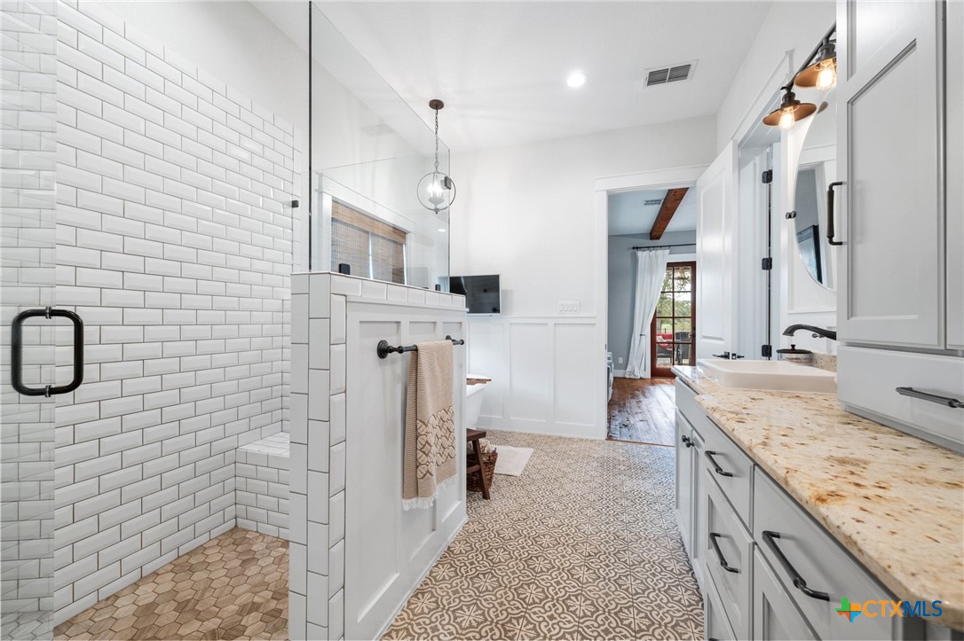 1665 Sunflower Trail Luling, TX 78648 - Photo 27 of 46 a spacious bathroom with a granite countertop sink a mirror and shower