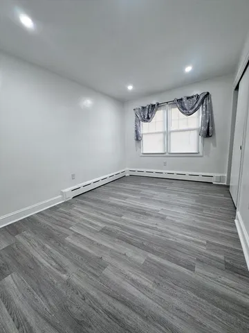an empty room with wooden floor and window