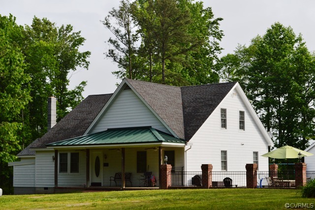 a view of a white house with a big yard and large trees