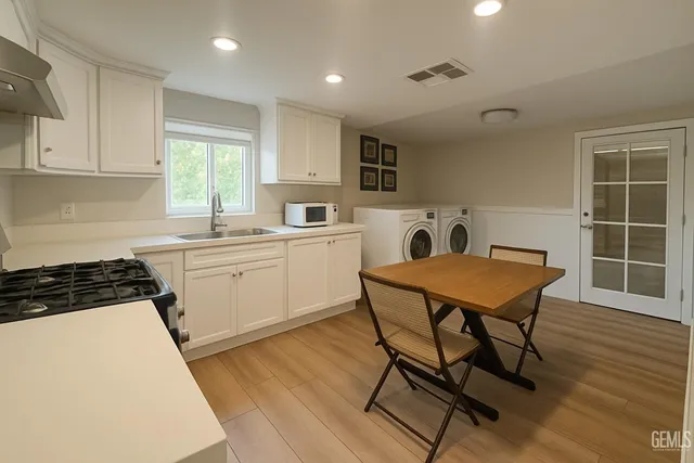 a kitchen that has a table chairs in it wooden cabinets and a window