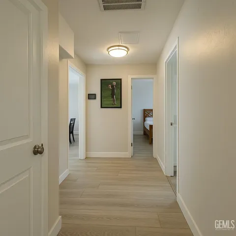 a view of a hallway with wooden floor and a bathroom