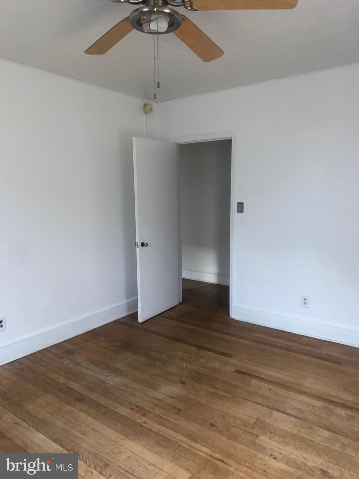5817 Keystone Street, Unit A Philadelphia, PA 19135 - Photo 8 of 27 an empty room with wooden floor ceiling fan and window