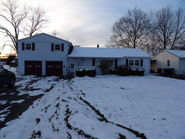 a front view of a house with a yard covered in snow