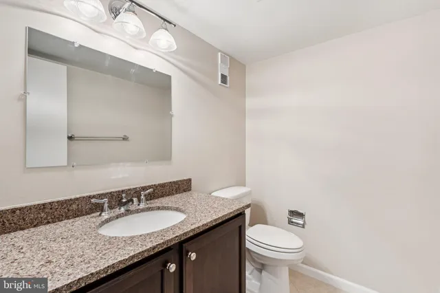 a bathroom with a granite countertop sink a toilet and a mirror