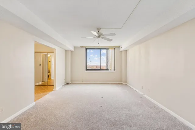 an empty room with windows and chandelier fan