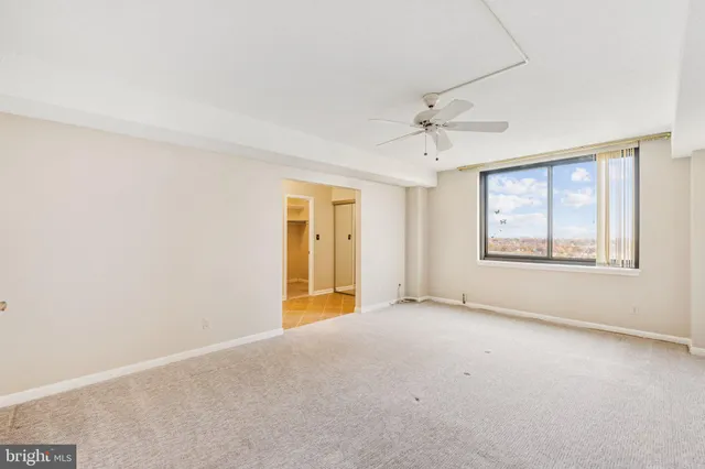 an empty room with windows and ceiling fan