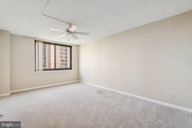 an empty room with windows and ceiling fan