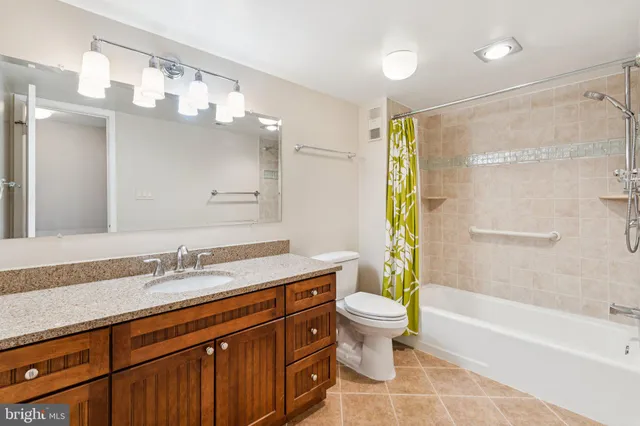 a bathroom with a granite countertop sink a toilet a mirror a bathtub and shower