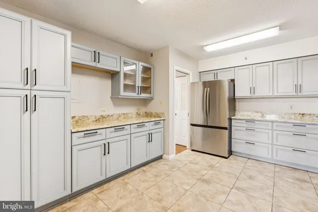 a kitchen with granite countertop a refrigerator sink stove and cabinets