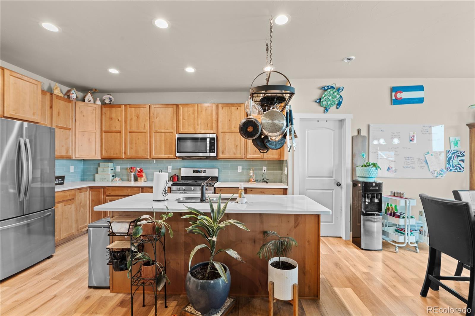 109 7th Avenue Wiggins, CO 80654 - Photo 4 of 38 a kitchen with stainless steel appliances granite countertop a refrigerator a sink dishwasher a dining table and chairs with wooden floor